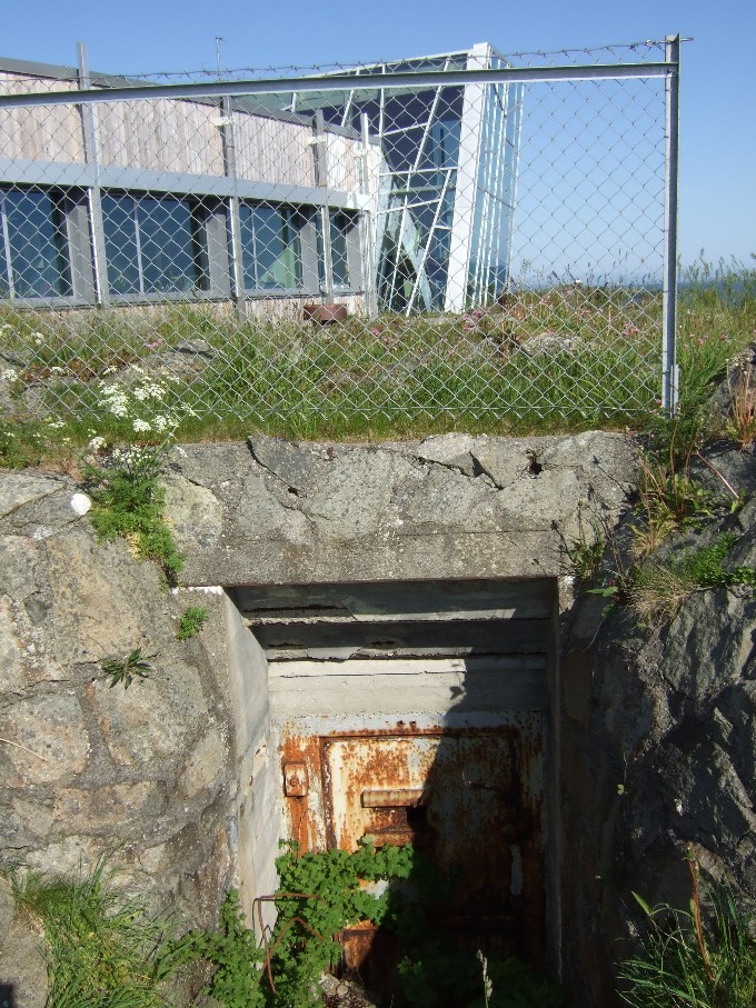 Inngang til bunker med kontorbygningen i bakgrunnen.