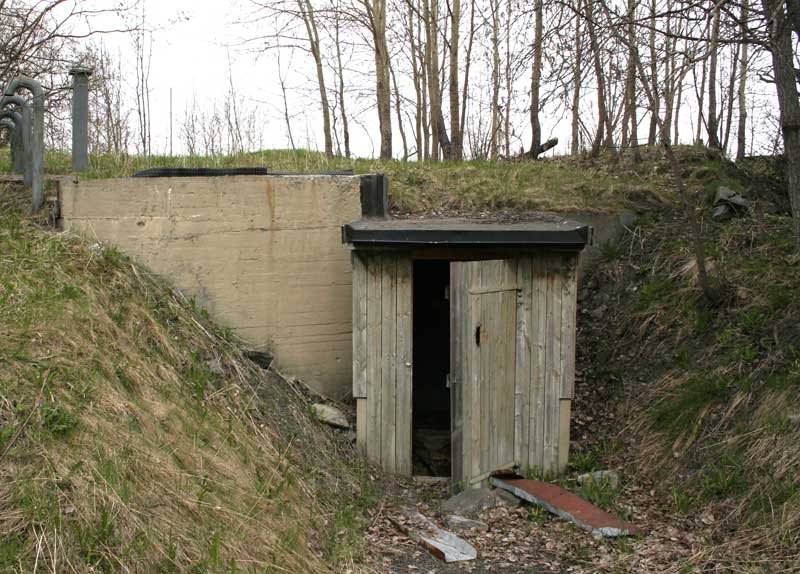 Inngangen. Døren er åpen, men bak denne er nok en dør (og ikke av tre). Klossen til venstre er ikke en del av regelbau, men en spesiell tillegg eller påført etter krigen.