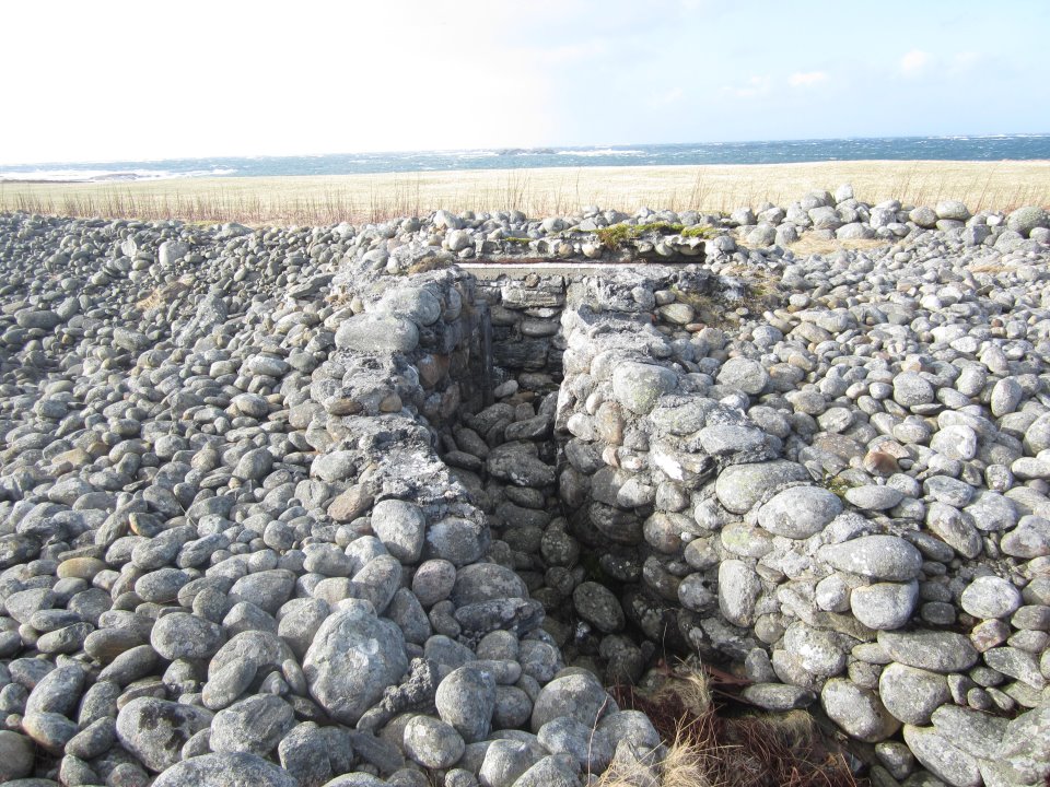 Løpegrav i betong/rullestein som fører inn til en mindre MG-bunker. Denne er sammenrast og delvis &quot;slukt&quot; av rullestein-stranden på Molnes.