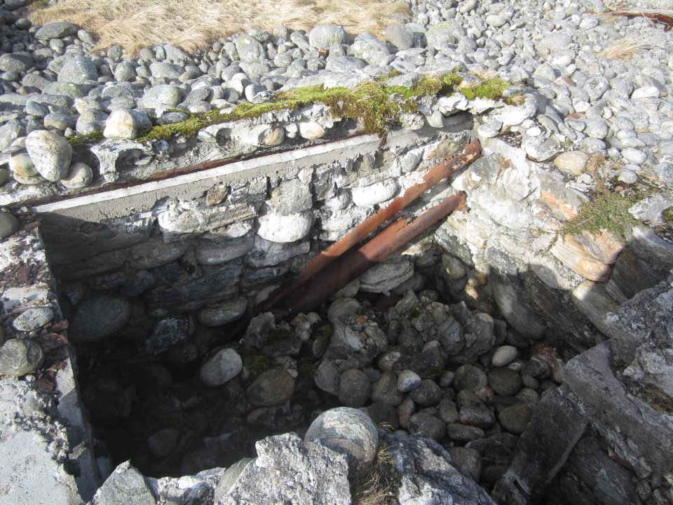 Mindre MG-bunker v. den nordligste FuMo 214 betongsokkelen.<br />Løpegrav i betong og rullestein fører inn til denne. Er sammenrast og delvis &quot;slukt&quot; av rullestein-stranden på Molnes. Taket var av bølgeblikkplater, torv, betong og rullestein.