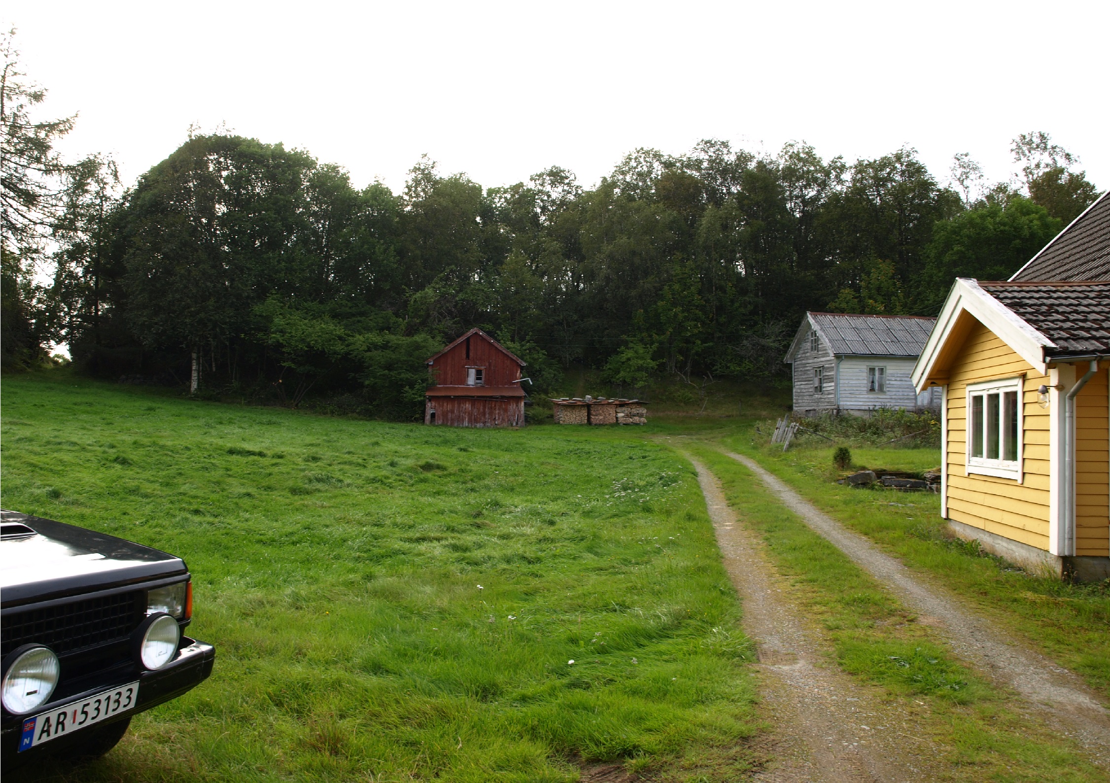 Vegen enda på detta småbruket her. Oppe til venstre kan en skimte vegen til kanonstillingane, på høgre og venstre side av denne vegen er det en bunker ( du ser sovidt i den på bildet). Det er også ein Bunker med utsyn over innkøyringa til gardstunet over det røde bygget. Opp til venstre er vegen til grottene og kanonstilling.