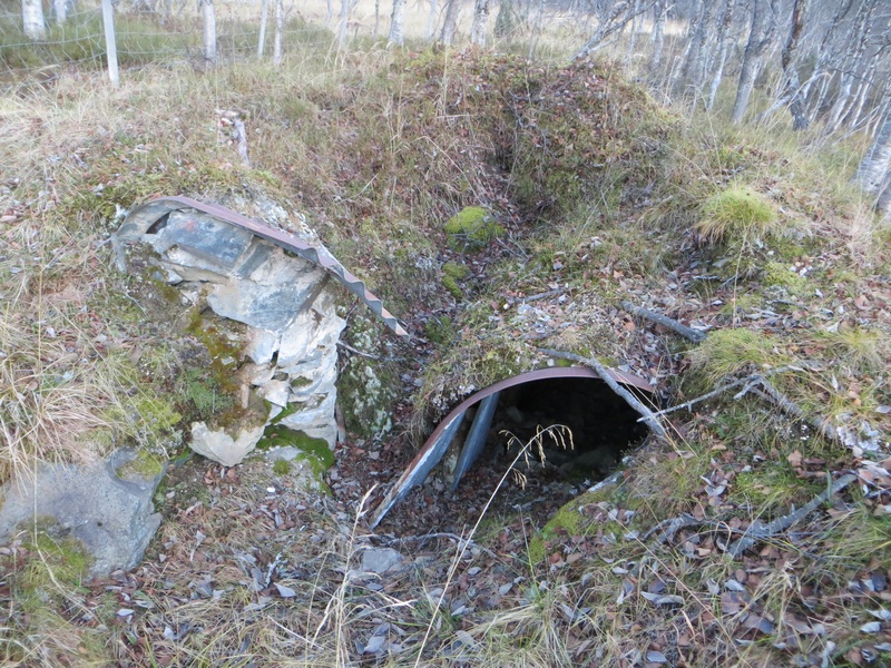 Delvis sammenrast bunker med rester av wellblech.