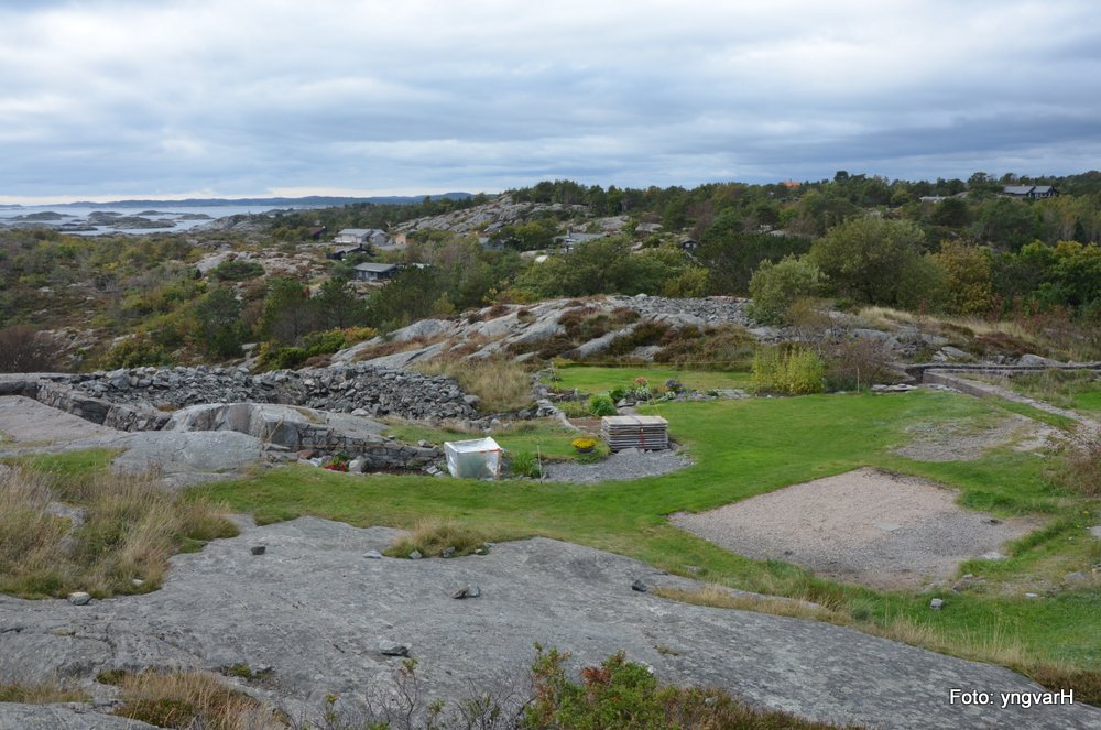 Plass for en campingvogn med fortelt, plen, blomster og grønnsakshage.